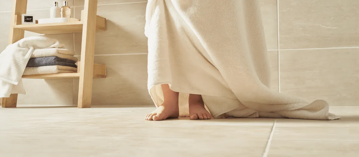 Person wrapped in a tile standing on tile floor in a bathroom