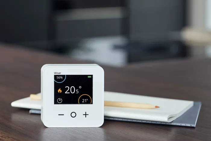 Wiser's smart thermostat next to a notepad andpencil