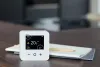 Wiser's smart thermostat next to a notepad andpencil